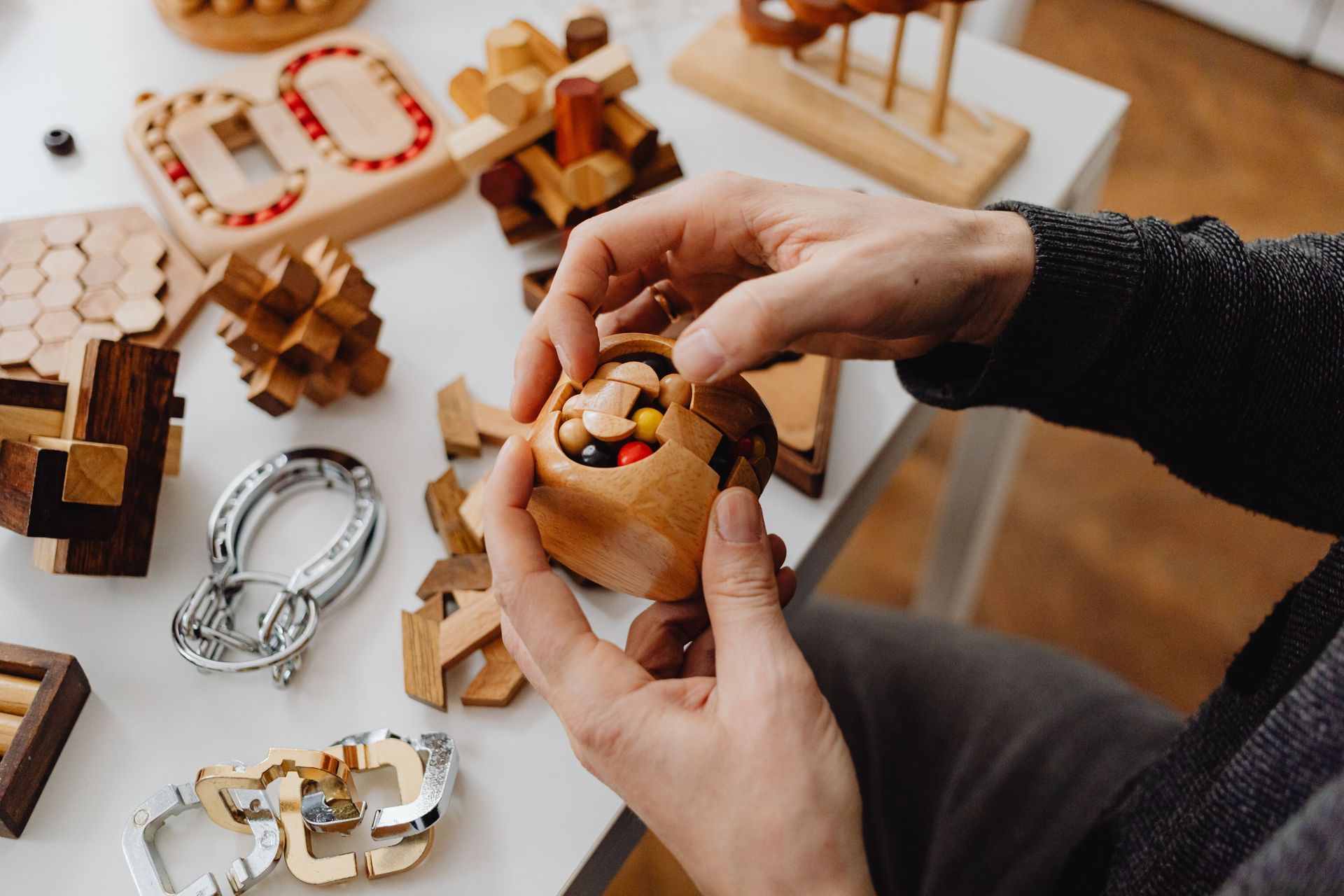 Person solving wooden puzzles with various toy designs. Perfect for mind games enthusiasts.