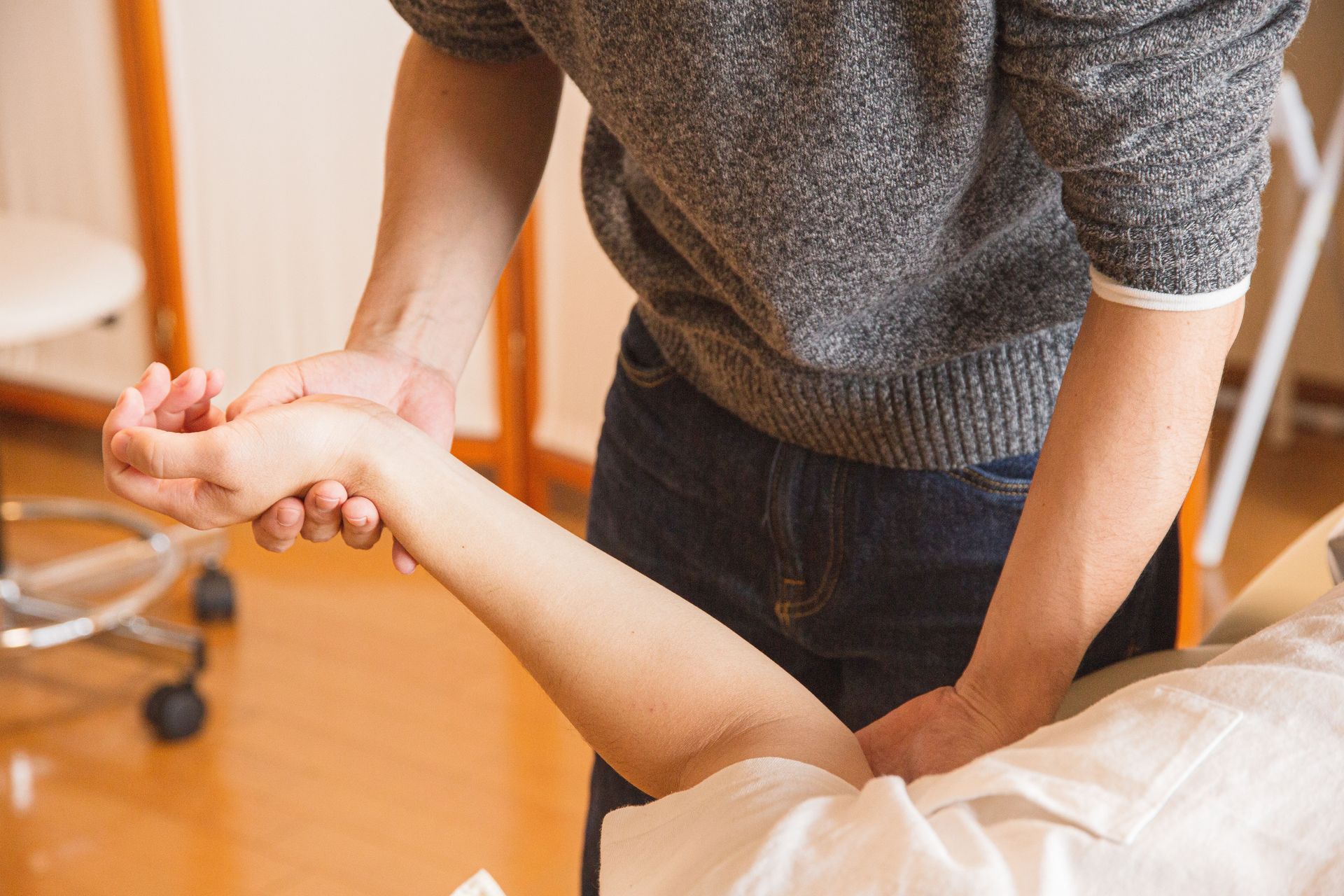 Crop anonymous osteopath massaging injured hand of client in process of treatment procedure